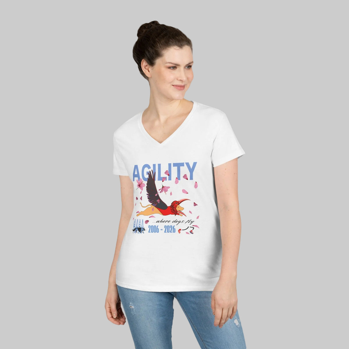 A woman modeling a black V-neck t-shirt with a white graphic print that reads 'AGILITY' and features a flying dog with a bird's mask on a white background.